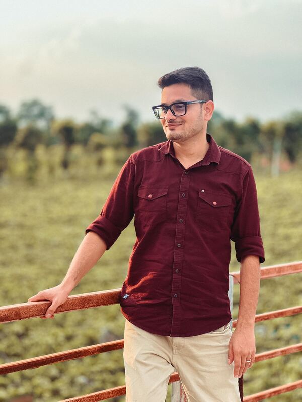 Bismay Ranjan Pradhan, standing at a railing beside a field.